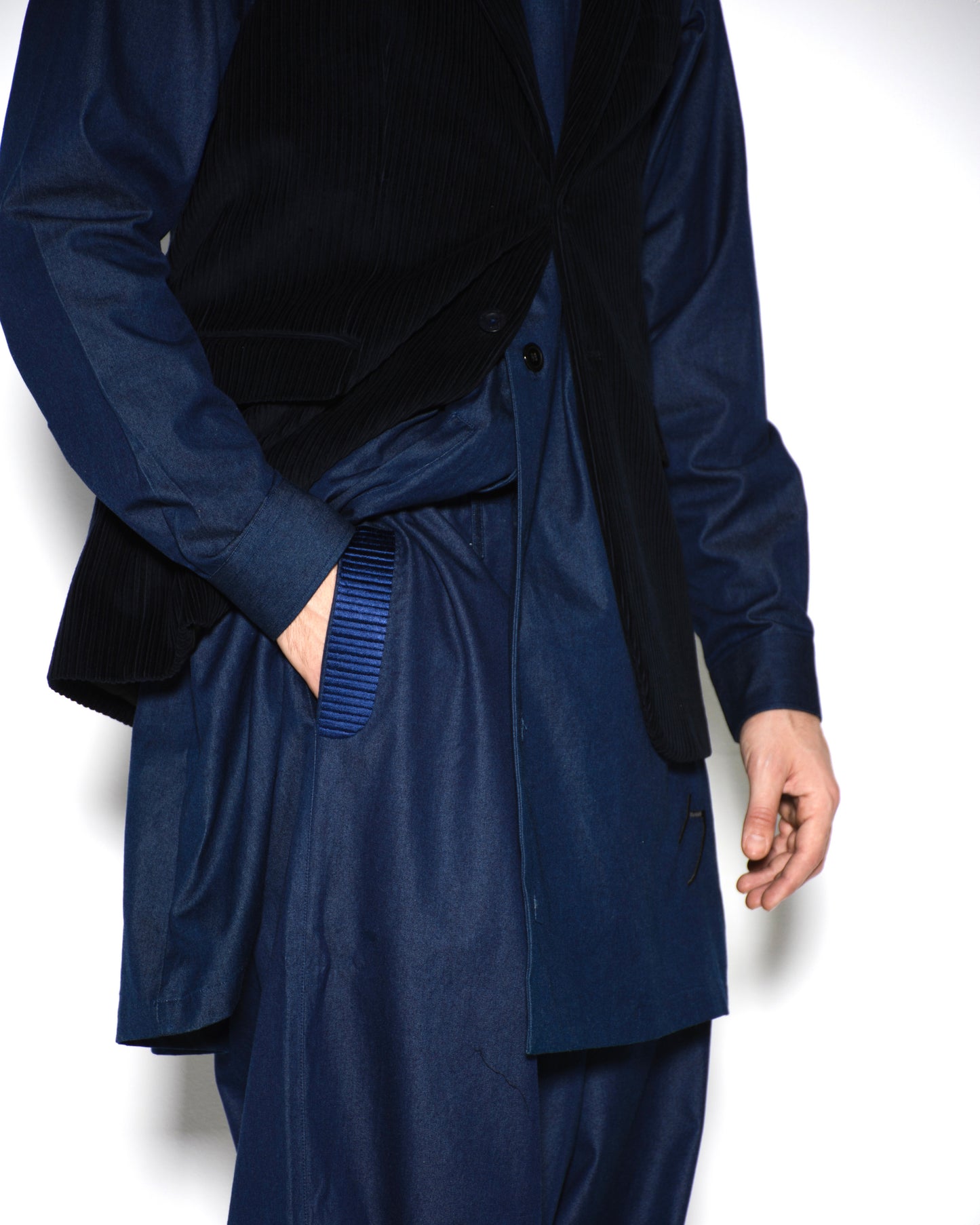 Person wearing a navy blue trench coat over a black shirt on a white background