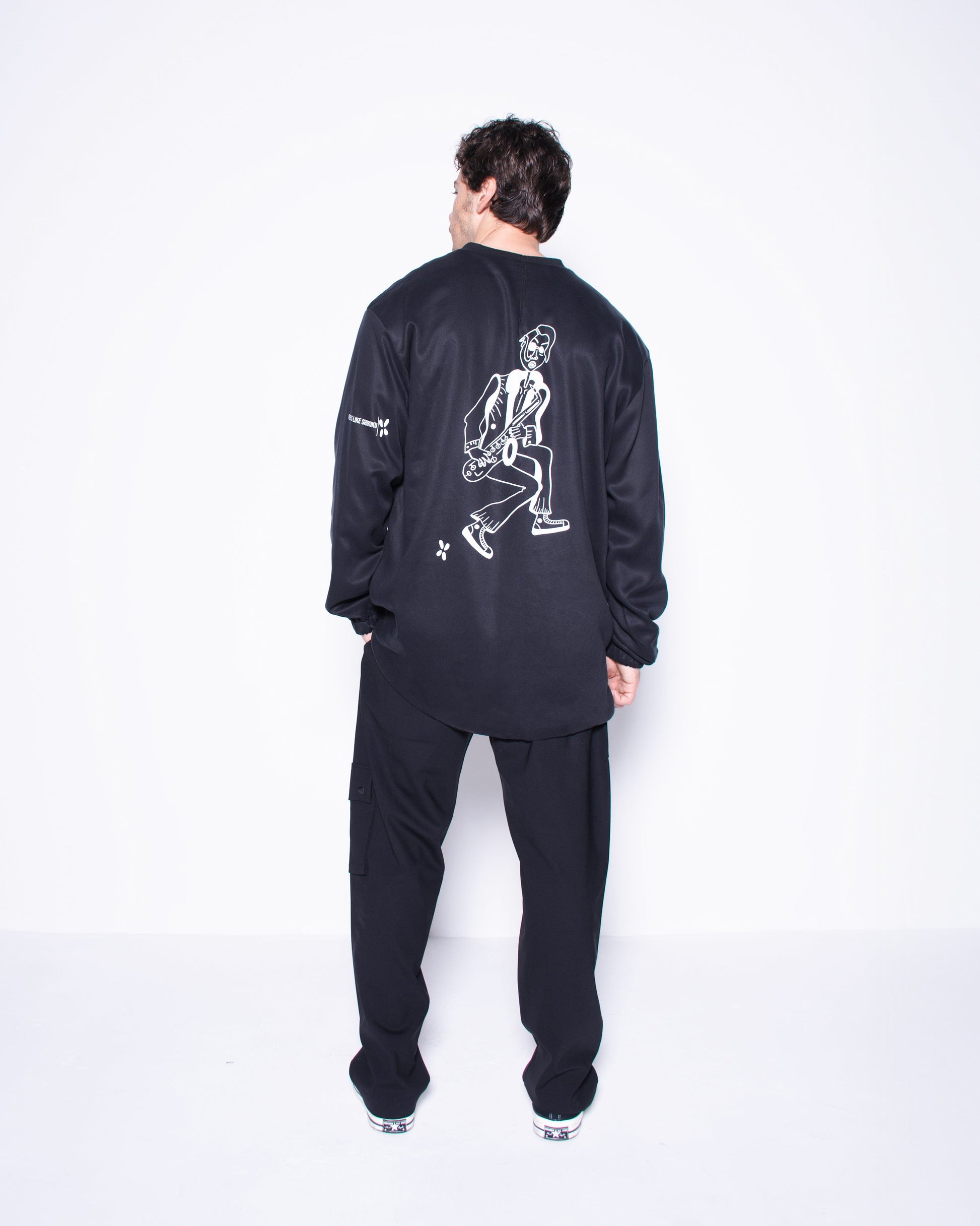 Person wearing a black tracksuit with white graphics on the back against a white background