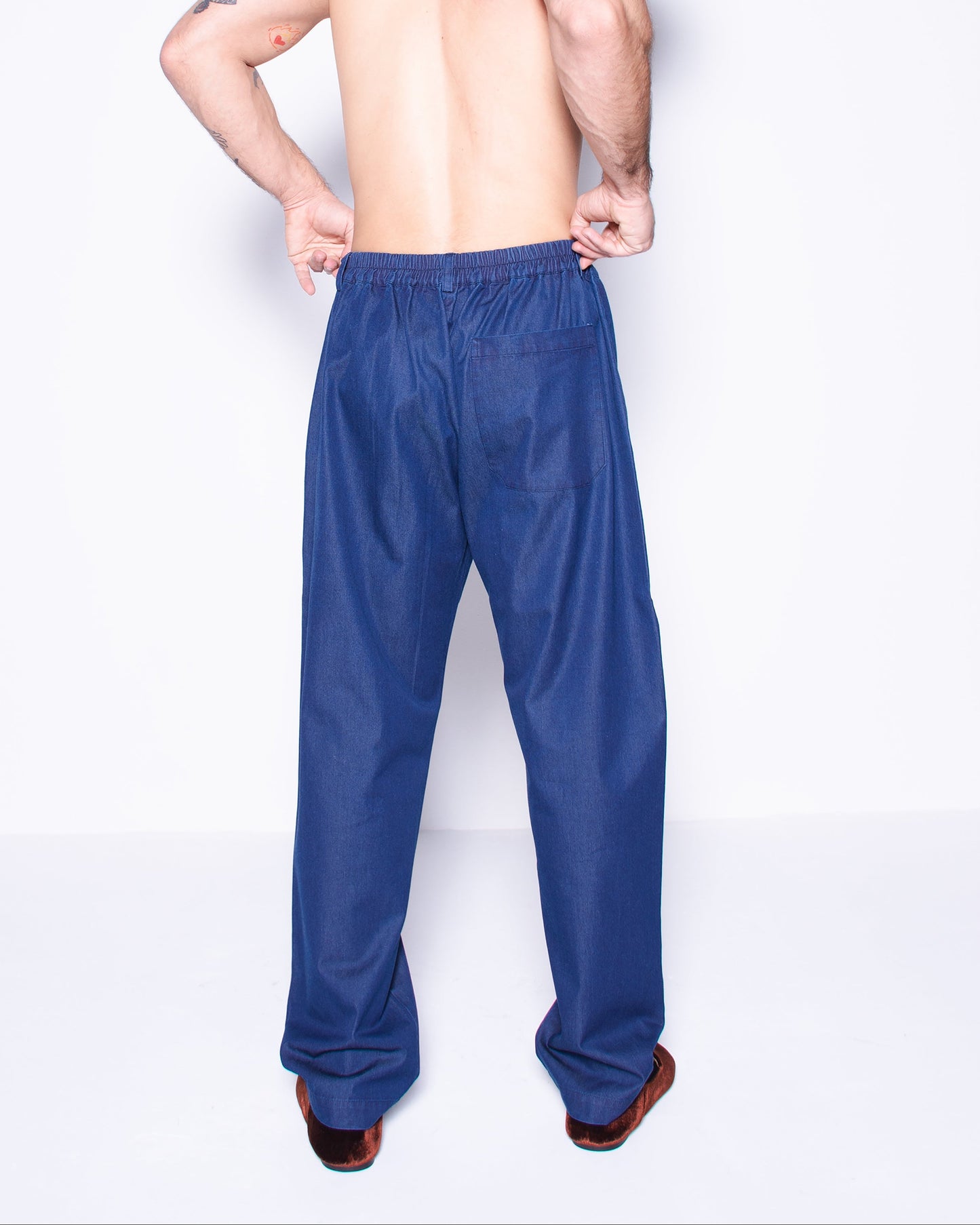 Man wearing blue silky ritorto denim pants on a white background