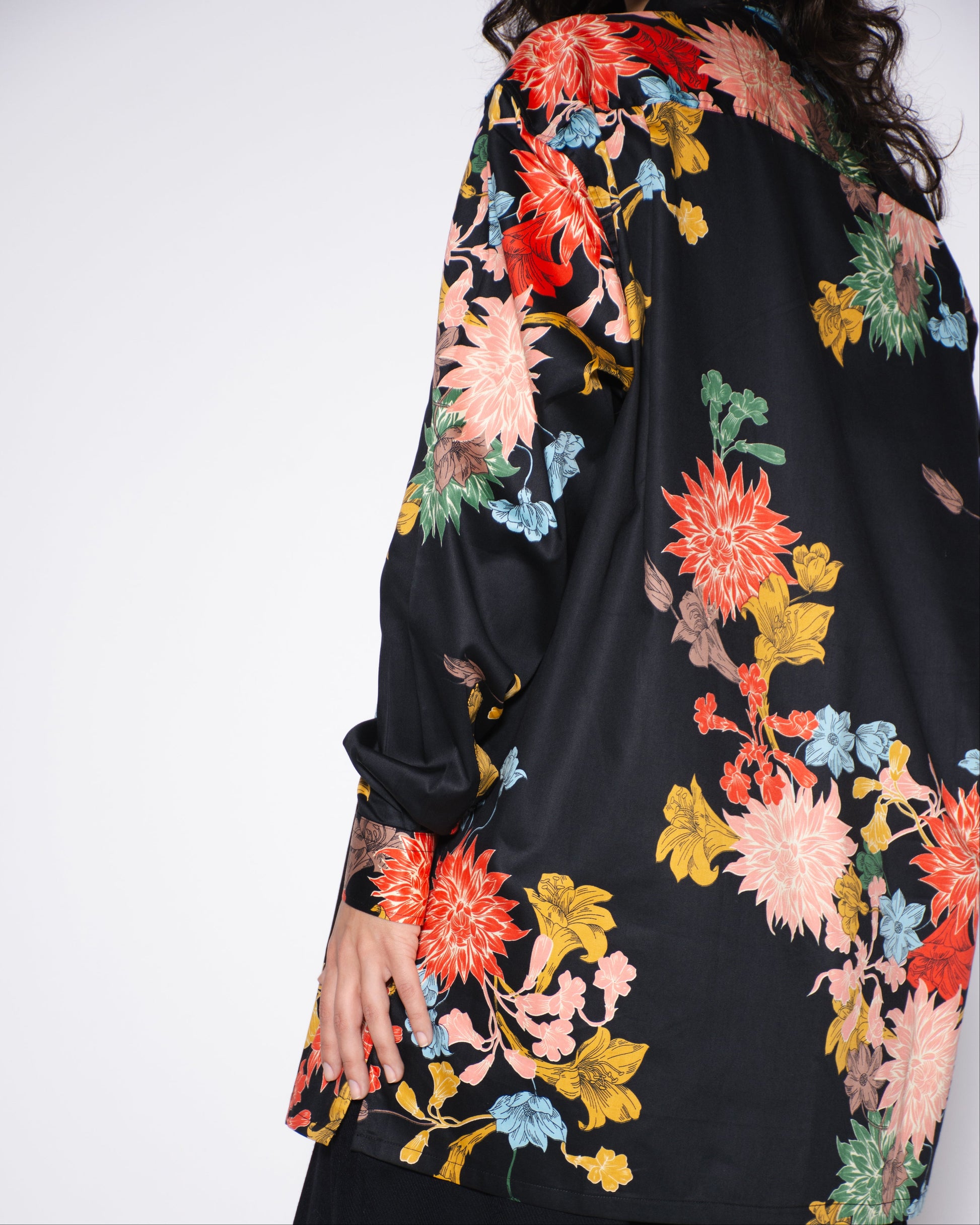 Black garment with colorful floral embroidery on a white background