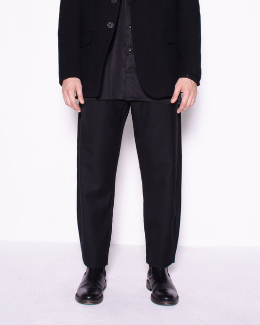 Man wearing a black suit standing against a white background