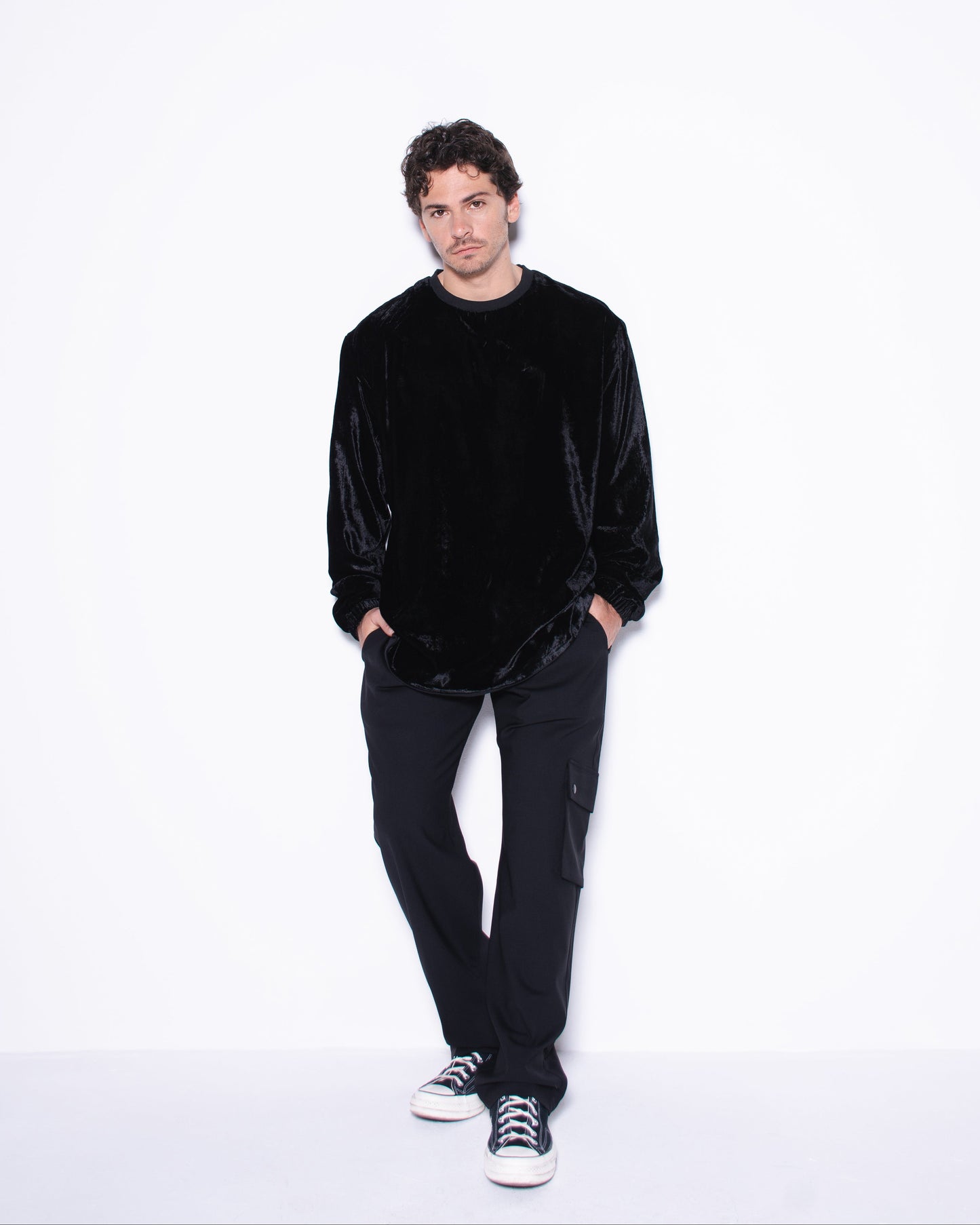 Man wearing a black velvet sweater and pants on a white background