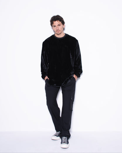 Man wearing a black velvet sweater and pants on a white background
