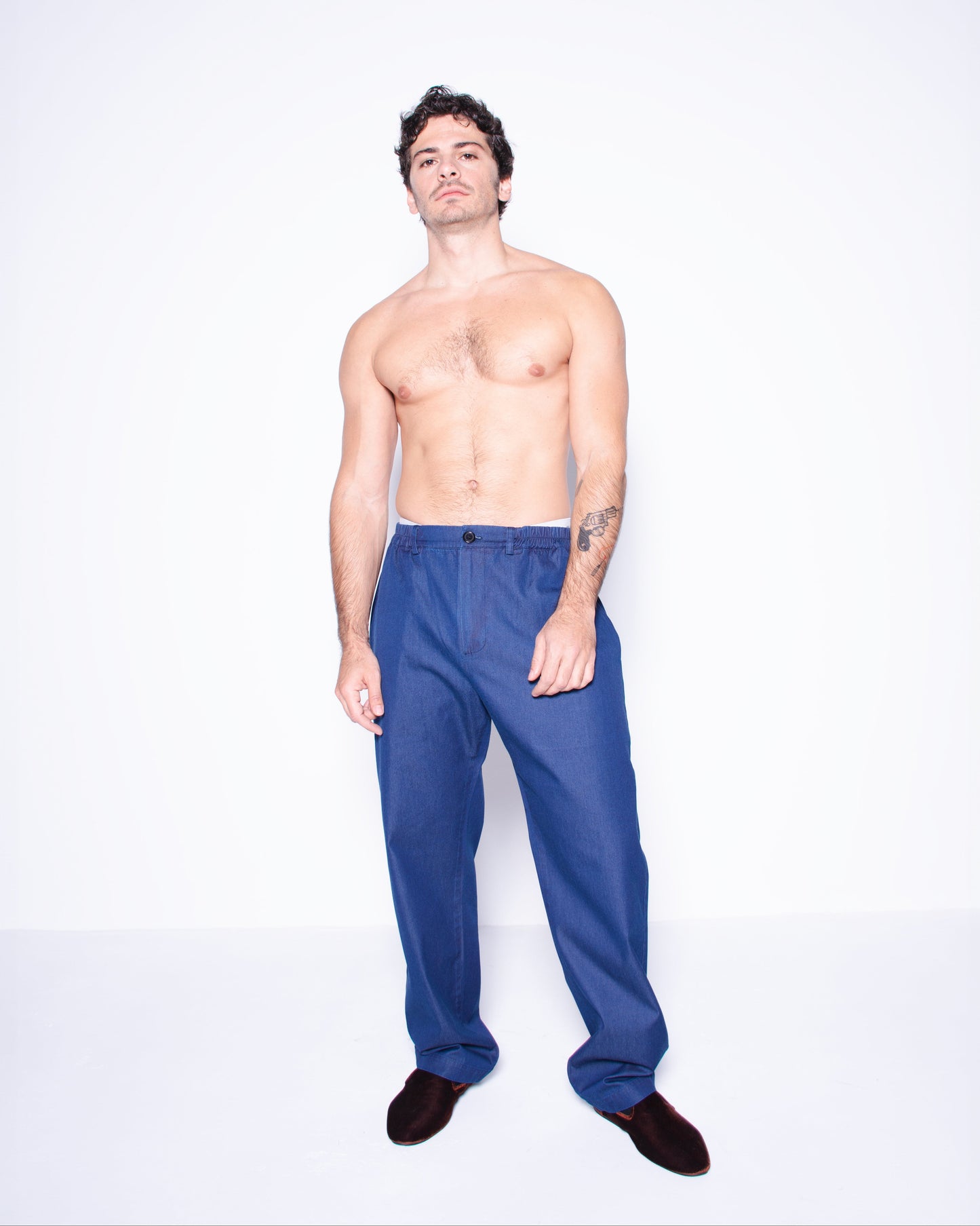 Man wearing blue silky ritorto denim pants on a white background