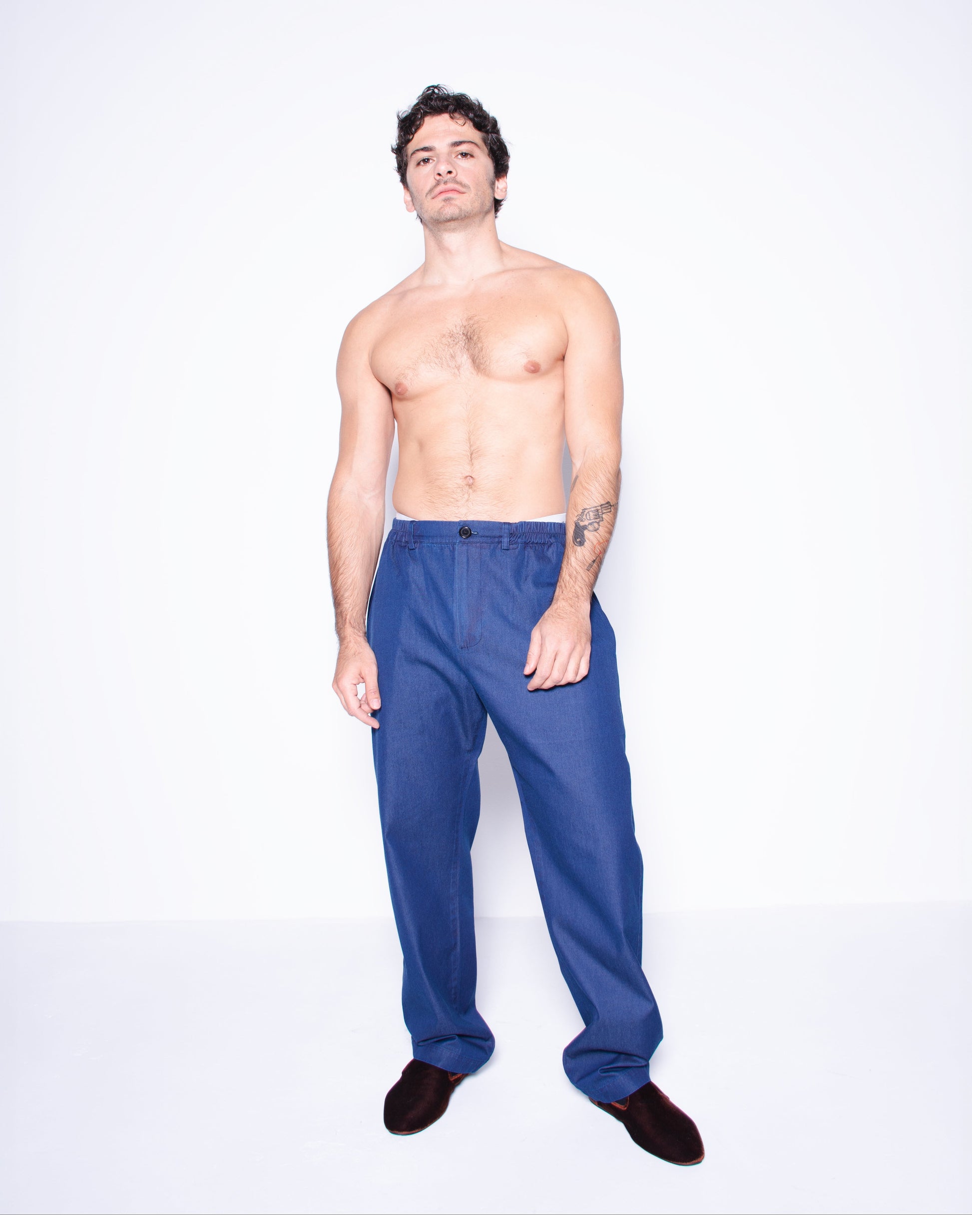 Man wearing blue silky ritorto denim pants on a white background
