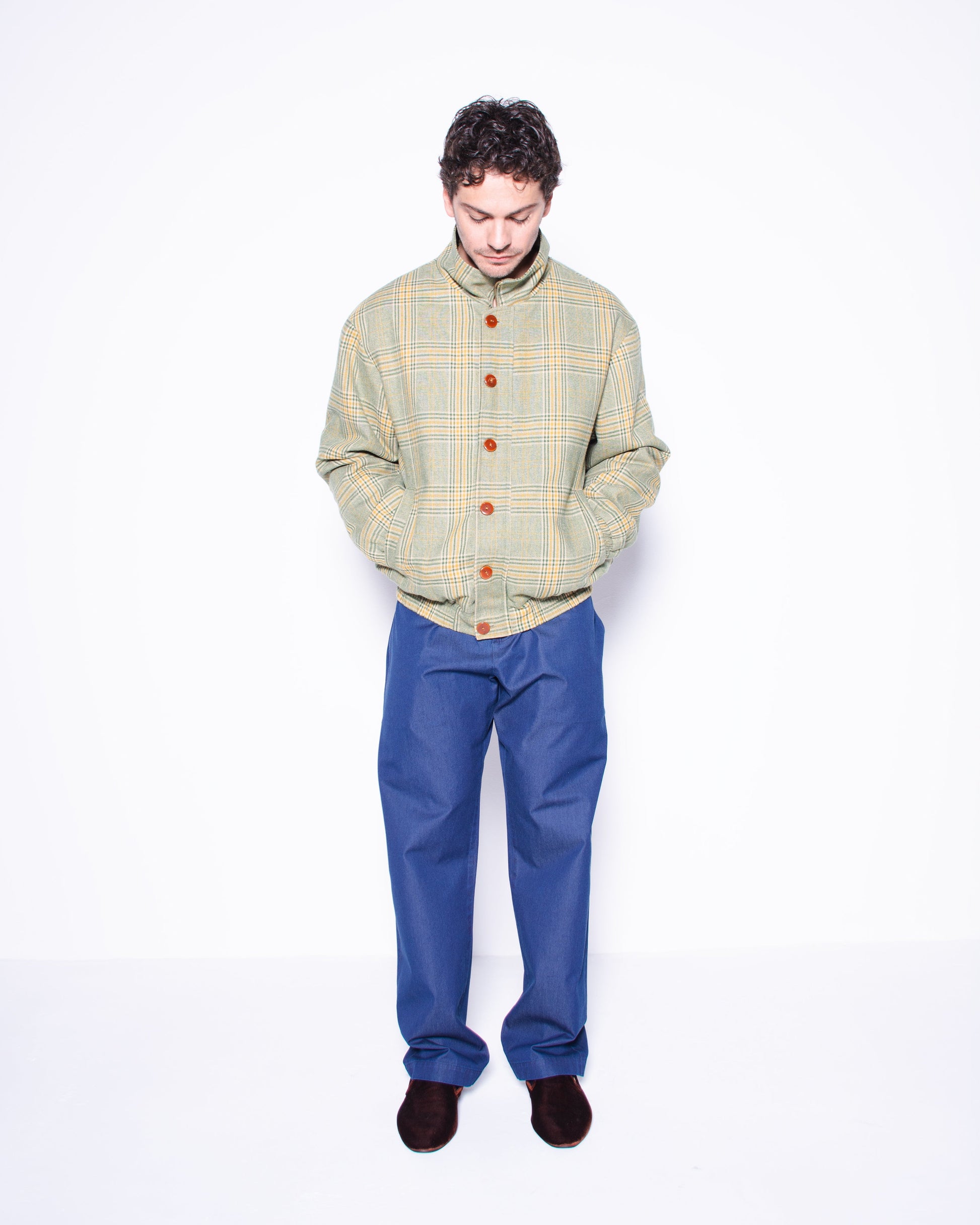 Man wearing a plaid jacket and blue silky ritorto denim pants on a white background