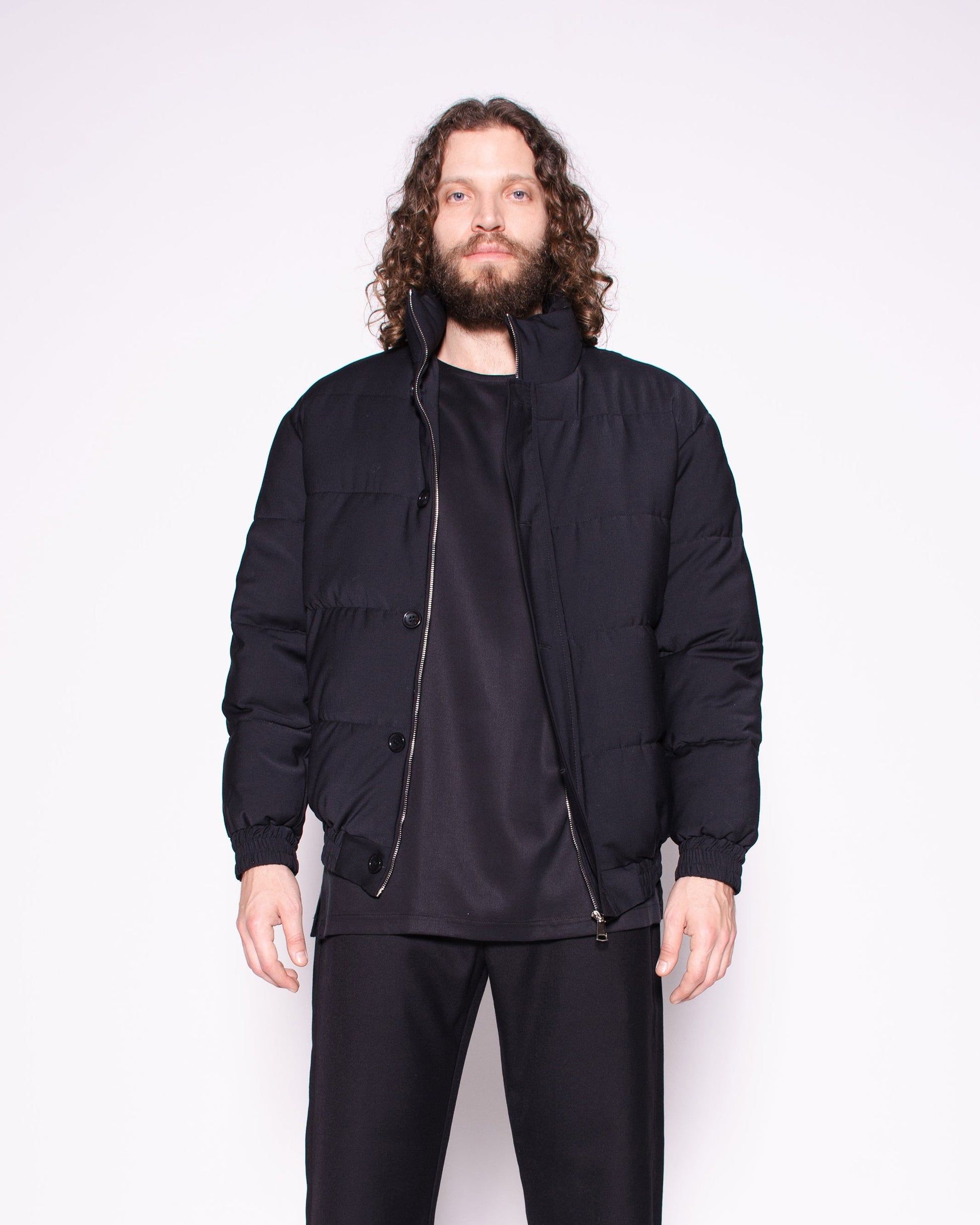 Man wearing a black jacket, pants, and shoes on a white background