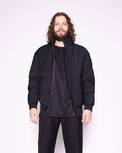 Man wearing a black jacket, pants, and shoes on a white background