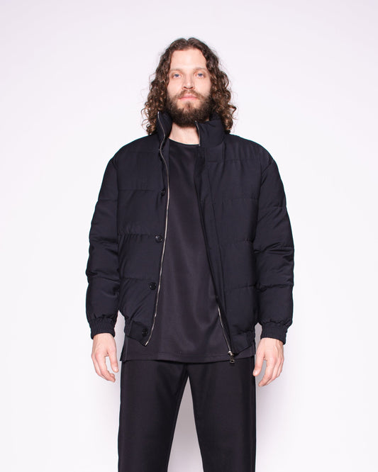 Man wearing a black jacket, pants, and shoes on a white background