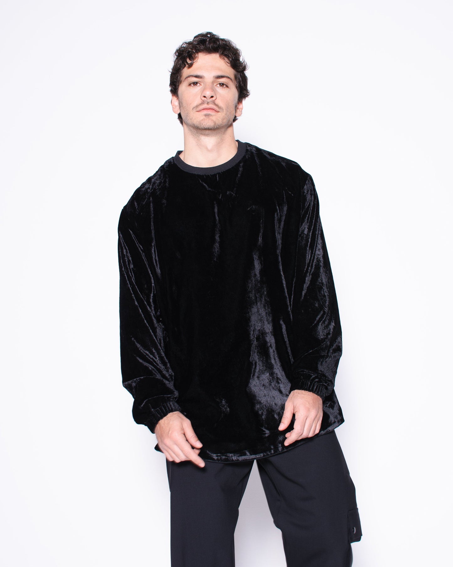 Person wearing a black velvet sweater and pants on a white background