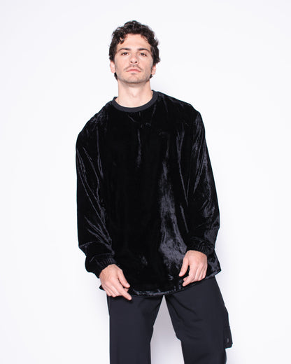 Person wearing a black velvet sweater and pants on a white background