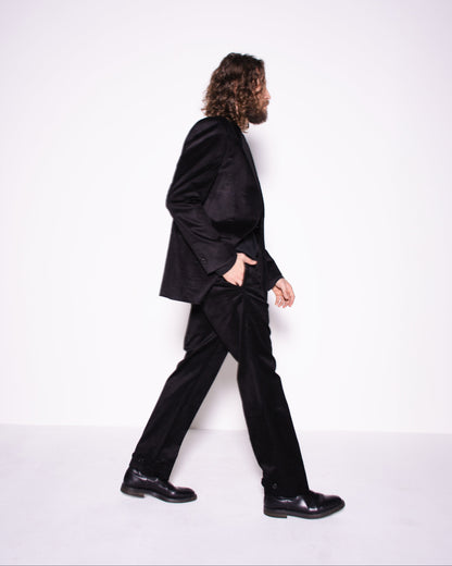 Person wearing a black suit walking on a white background