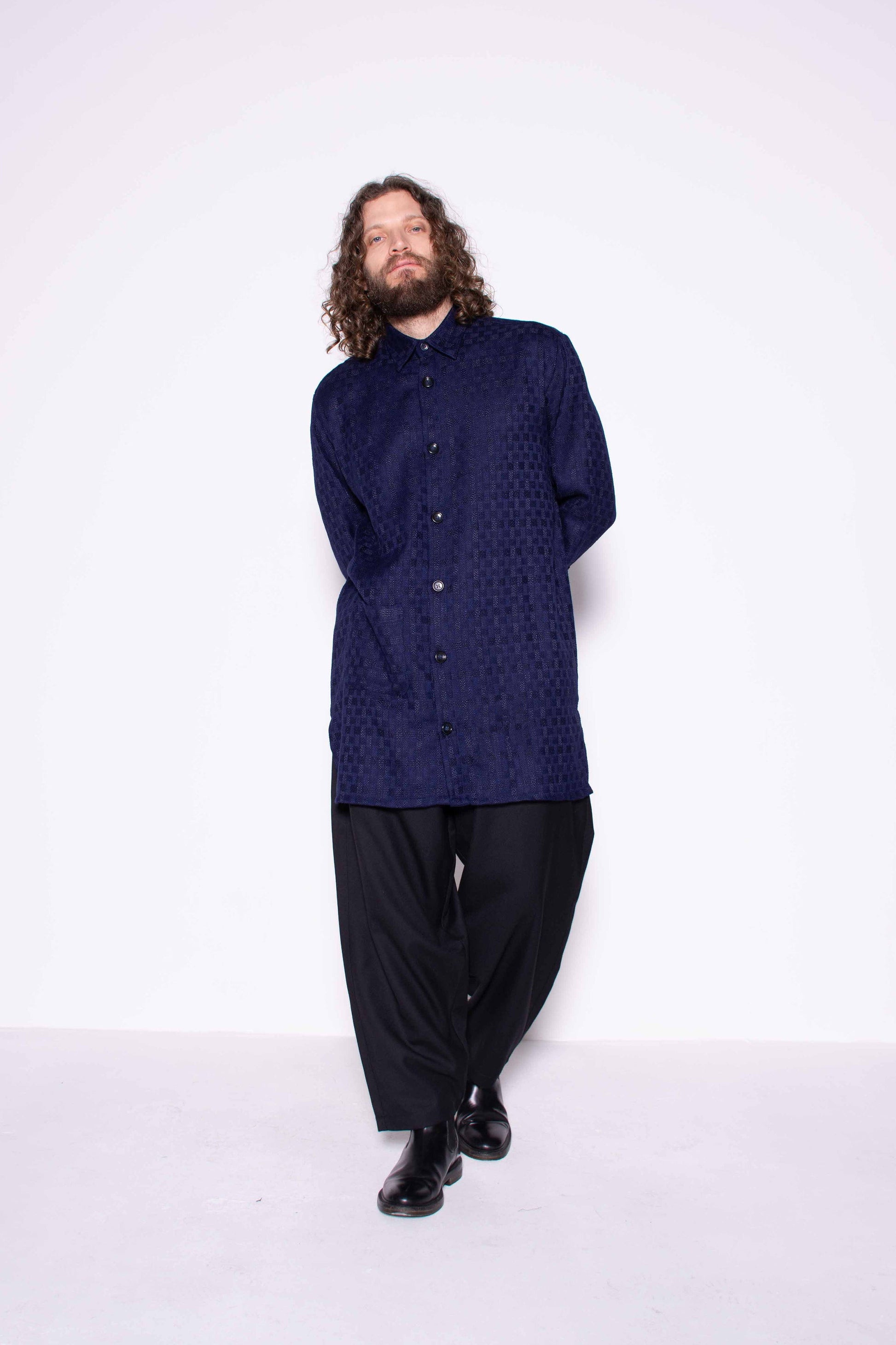 Person wearing a dark blue shirt and black pants on a white background