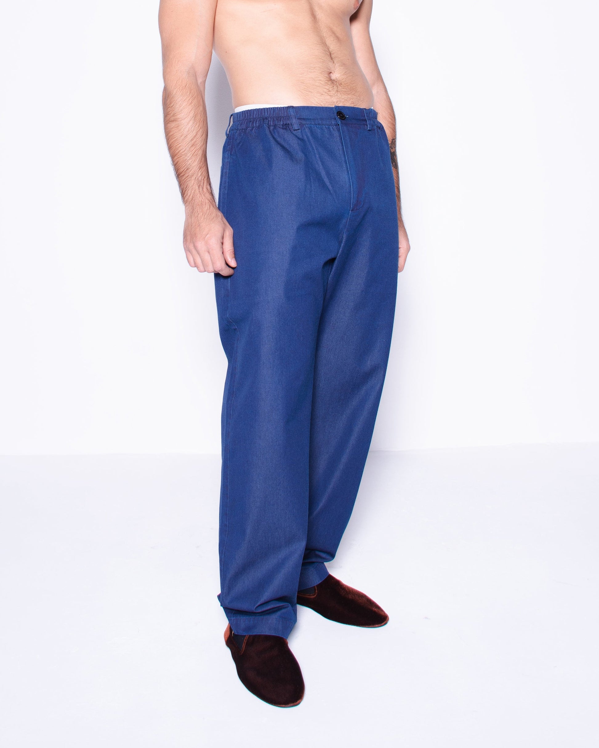 Man wearing blue silky ritorto denim pants on a white background