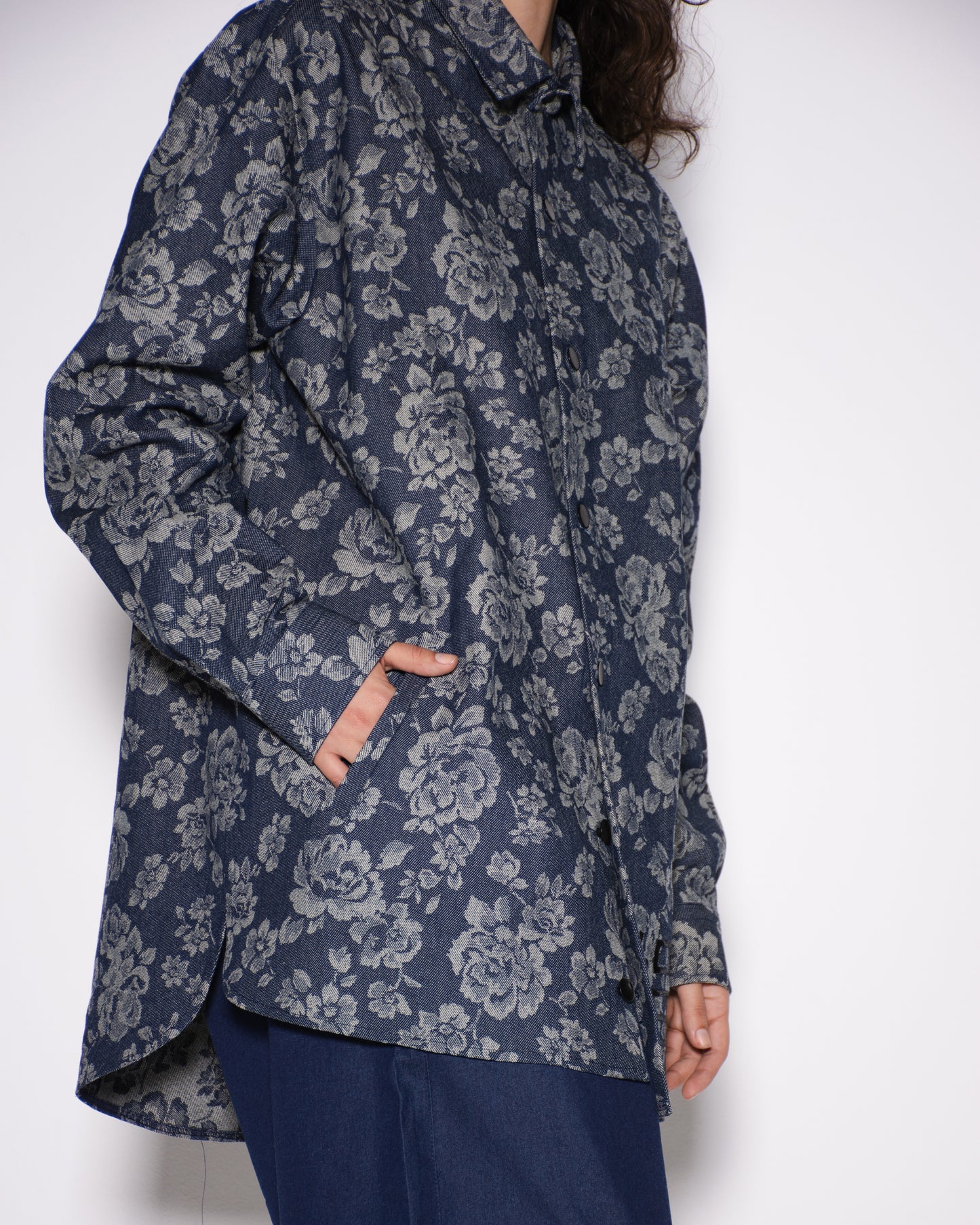 Person wearing a dark floral patterned shirt against a white background