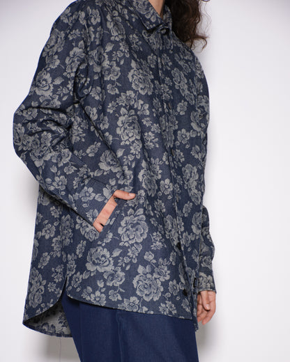 Person wearing a dark floral patterned shirt against a white background