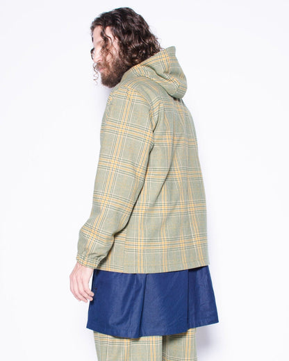 Person wearing a plaid coat and pants with a blue skirt underneath on a white background