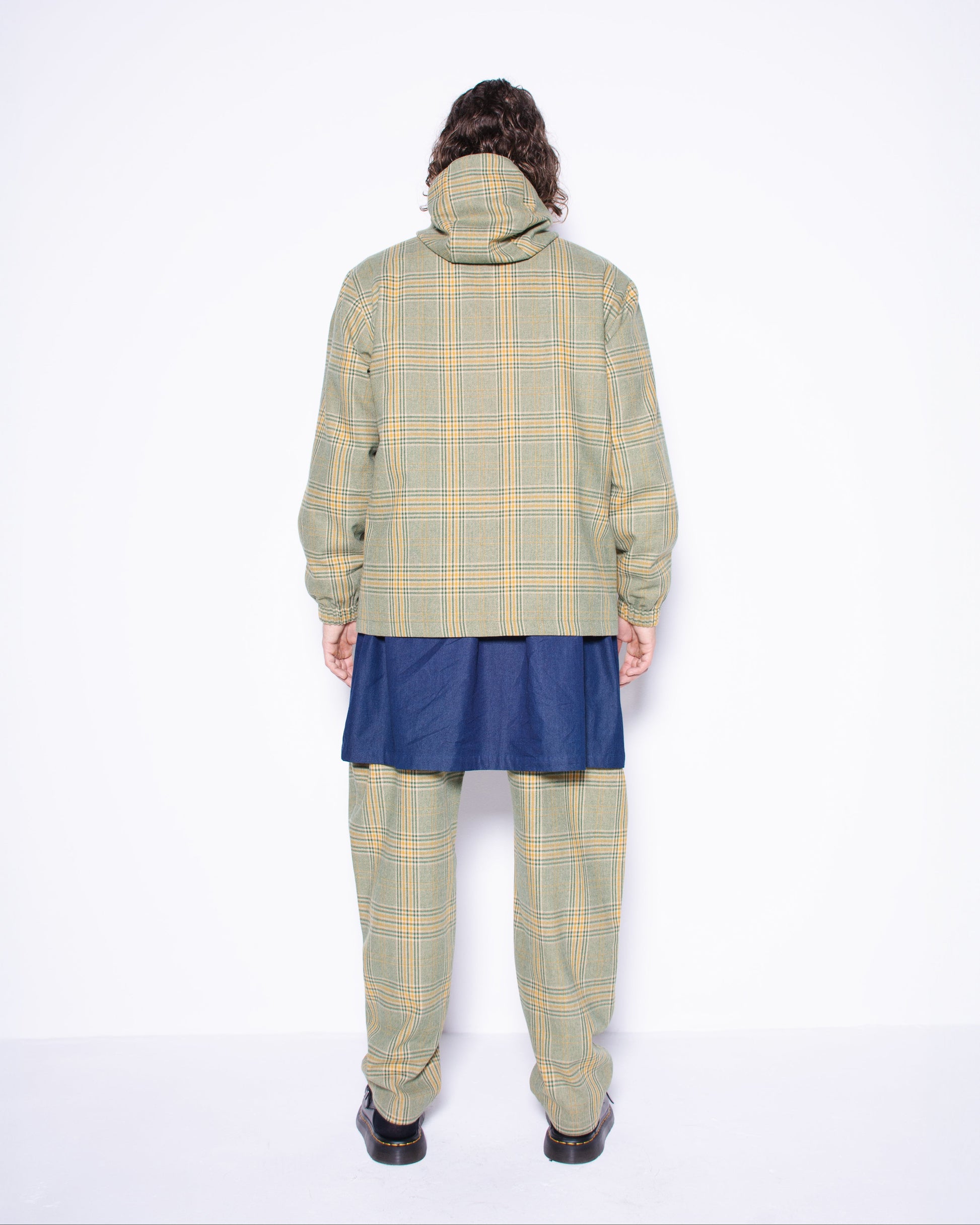  Person wearing green english wool striped  plaid coat and pants with a blue skirt underneath on a white background