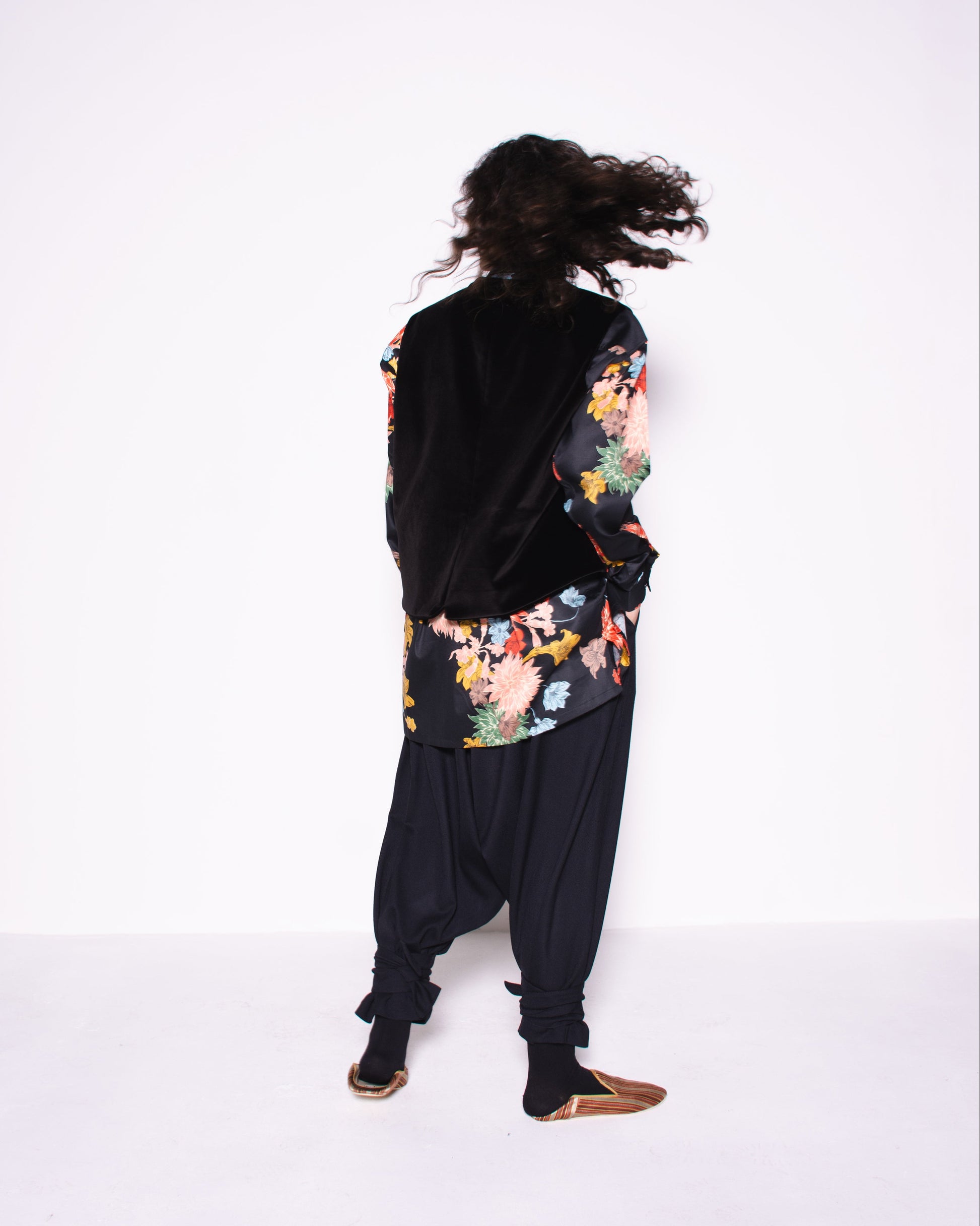 Person wearing a black outfit with colorful floral patterns on a white background