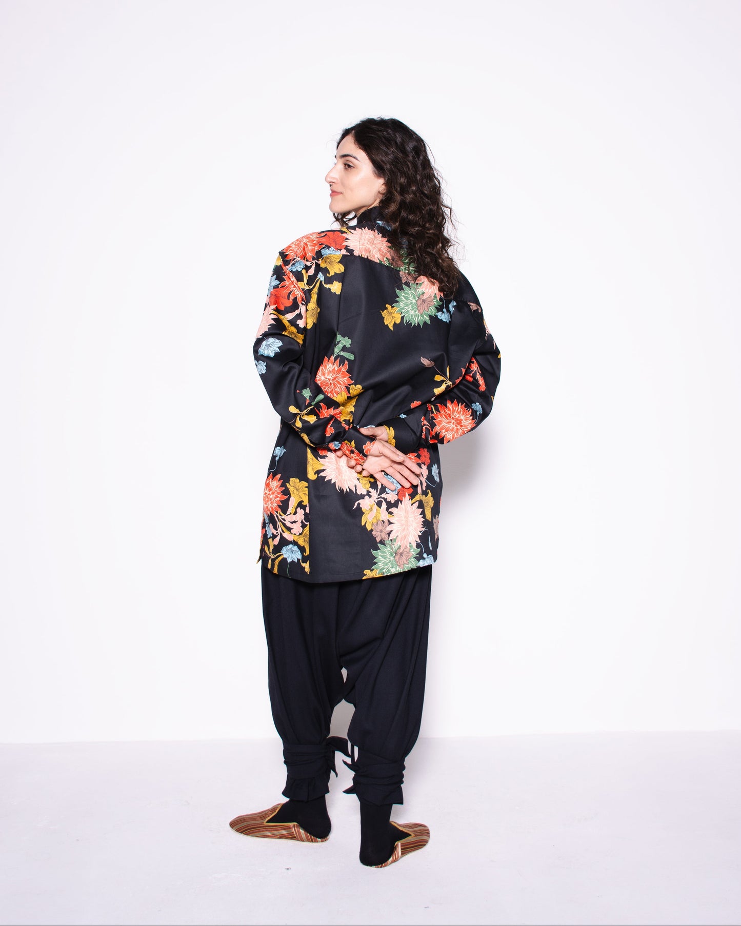 Woman wearing a floral jacket and black pants on a white background