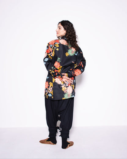 Woman wearing a floral jacket and black pants on a white background