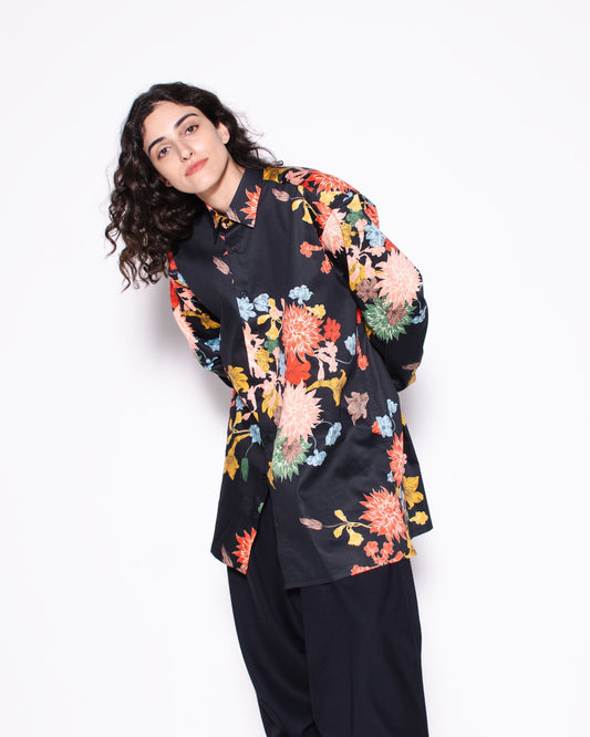 Woman wearing a black floral blouse and black pants on a white background