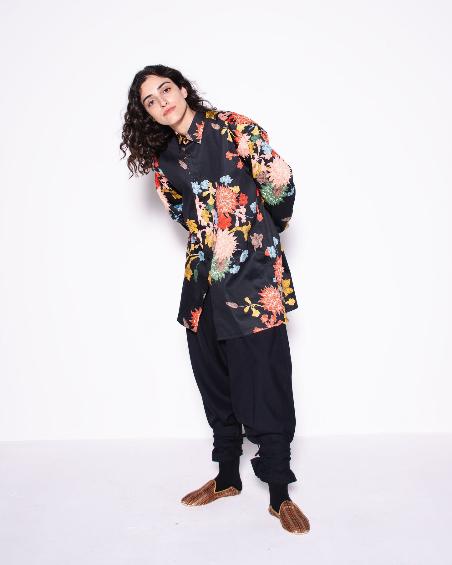 Woman wearing a black floral blouse and black pants on a white background