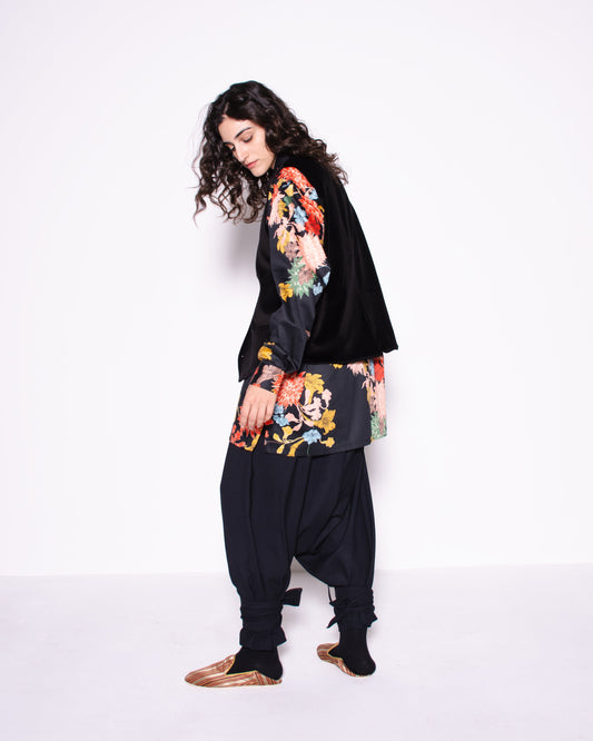 Person wearing a black outfit with colorful floral patterns on a white background