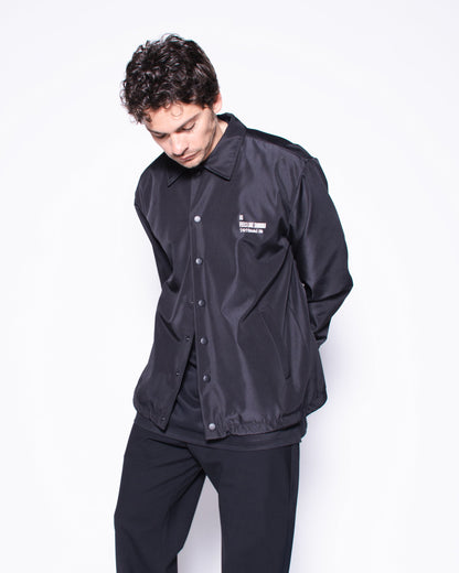 Person wearing a black outfit with a brand logo on a white background