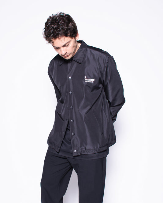 Person wearing a black outfit with a brand logo on a white background