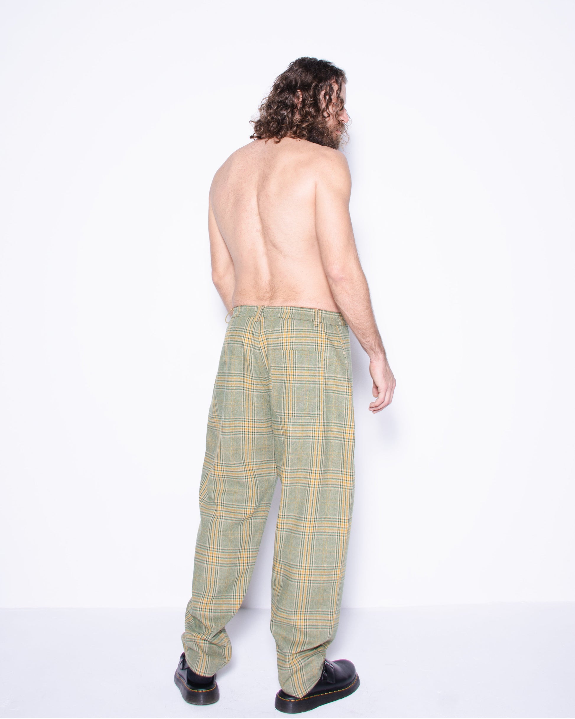  Person wearing green english wool striped  plaid coat and pants with a blue skirt underneath on a white background